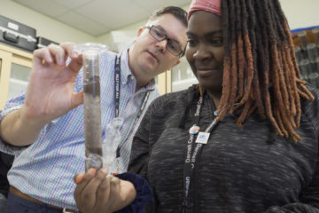 Photo shows Dr. Sowell assisting a student with lab work.