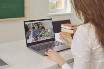 Stock image of parent and child chatting with teacher virtually