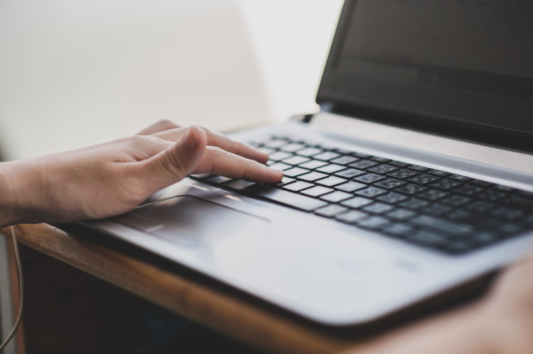 Image shows close up of hand typing on a laptop