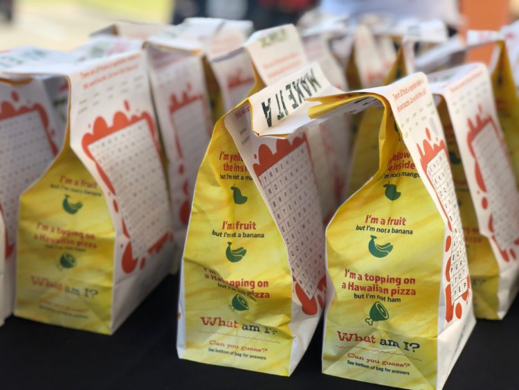 Photo shows rows of to go school lunch bags.