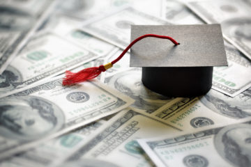 Stock photo of a graduation cap on top of dollar bills