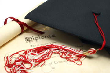 Photo of a graduation cap on top of a diploma