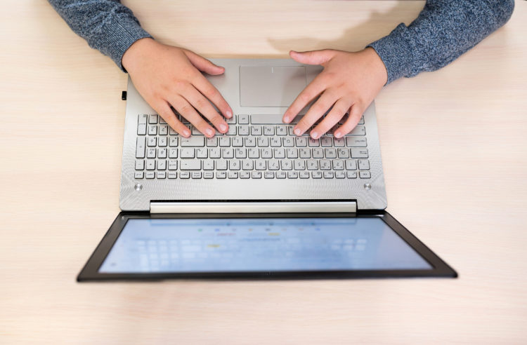 Photo shows overhead shot of hands on laptop keyboard