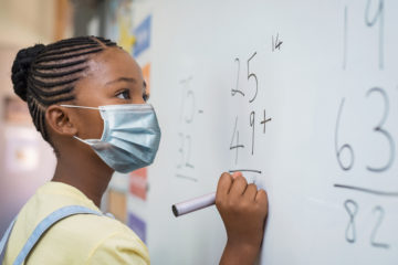 Student at whiteboard with face mask