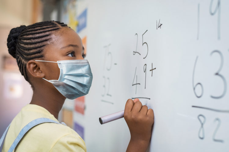 Student at whiteboard with face mask