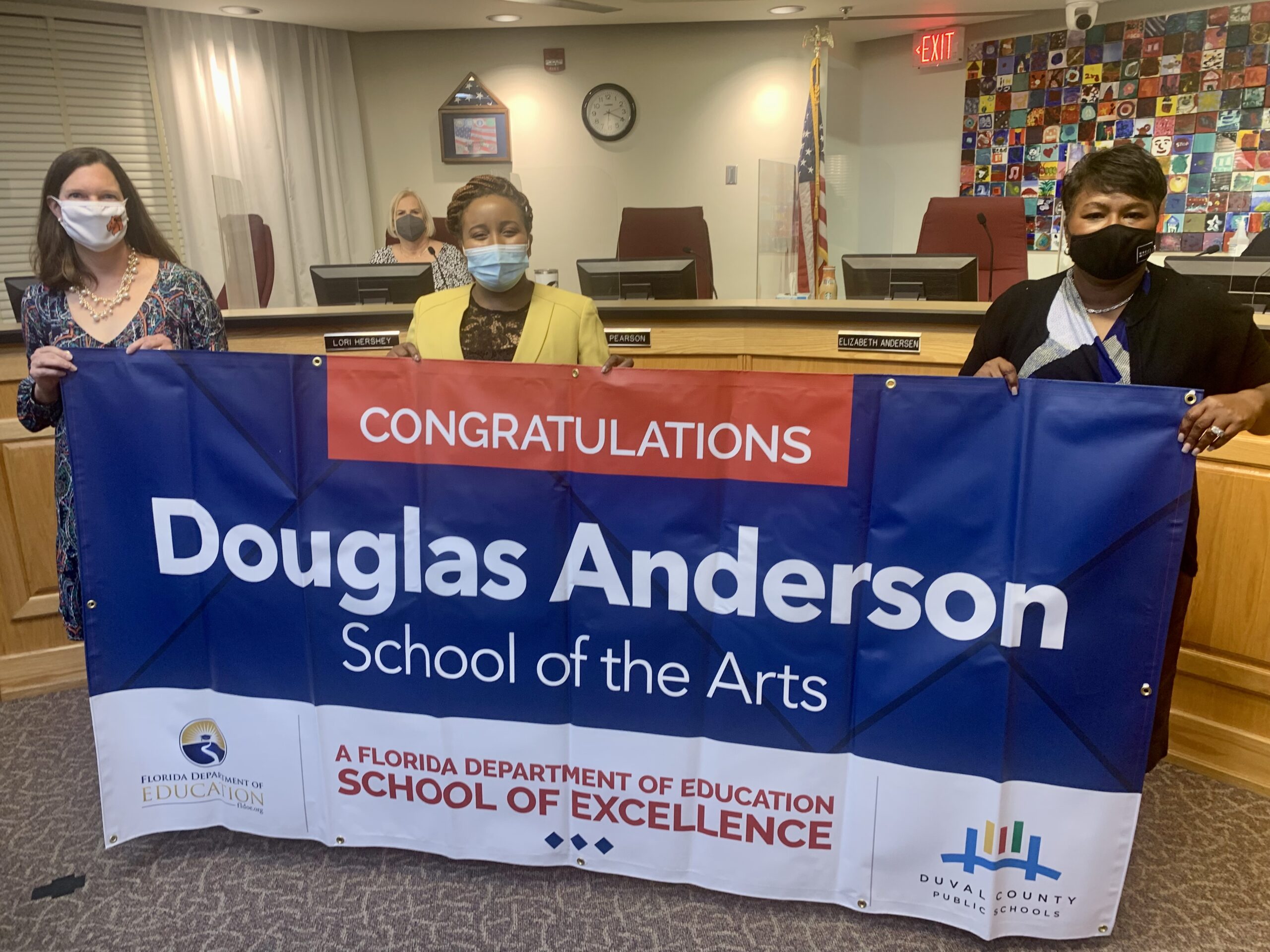 Superintendent, Board Member and school administrator hold banner Congratulations Douglas Anderson School of the Arts a Florida Department of Education School of Excellence