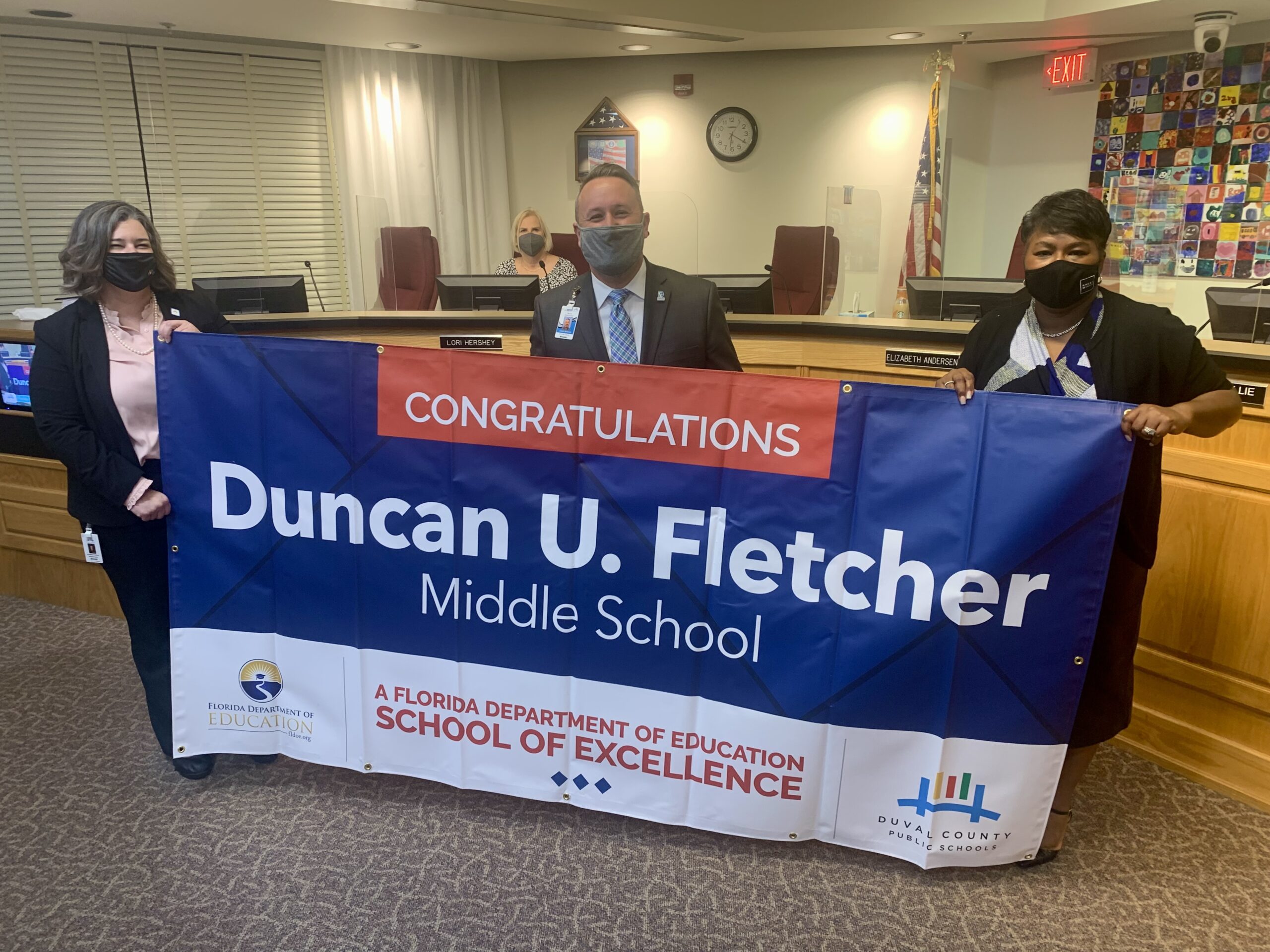 Superintendent, Board Member and school administrator hold banner Congratulations Duncan U. Fletcher Middle School a Florida Department of Education School of Excellence