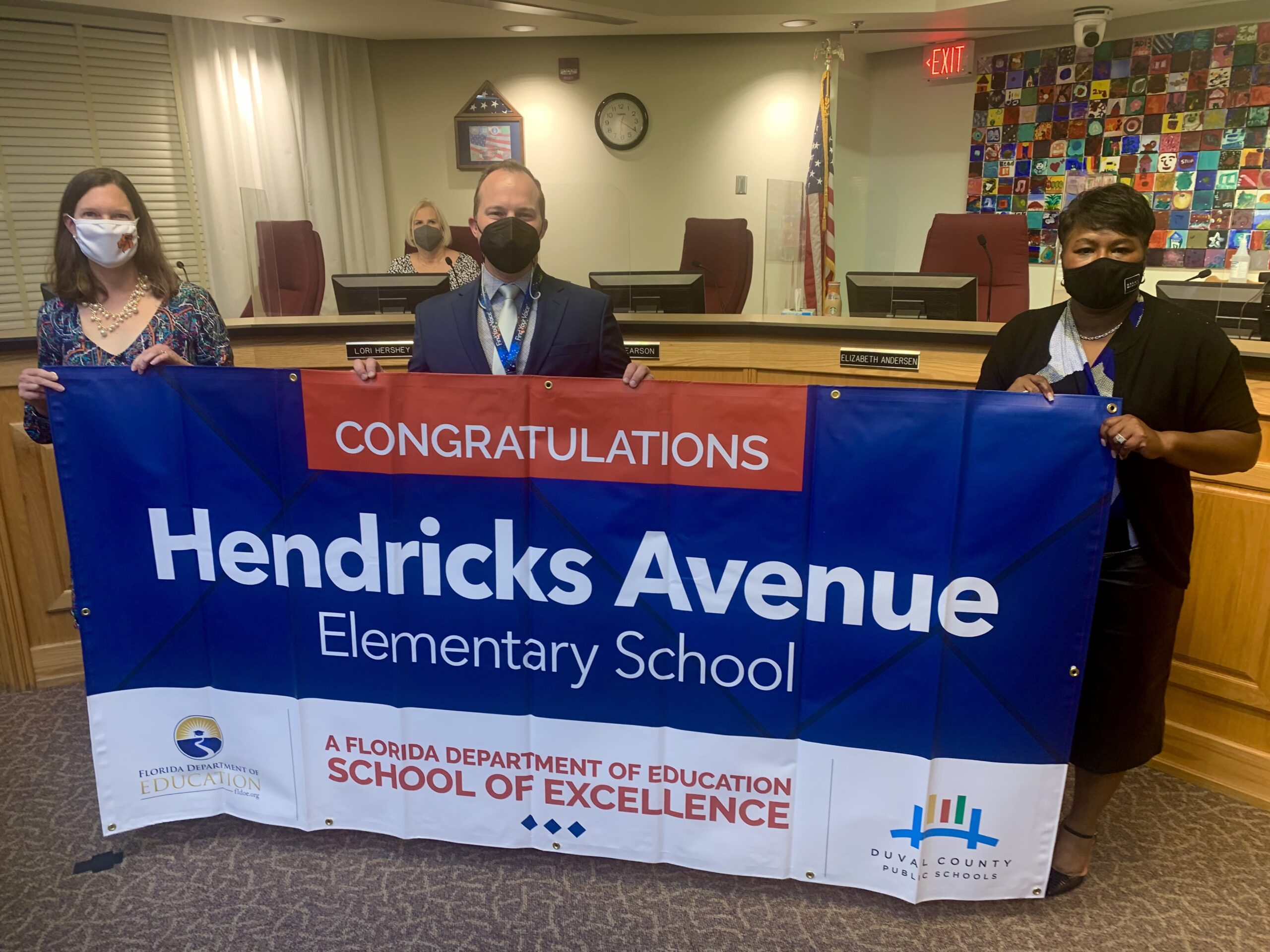 Superintendent, Board Member and school administrator hold banner Congratulations Hendricks Avenue Elementary School a Florida Department of Education School of Excellence