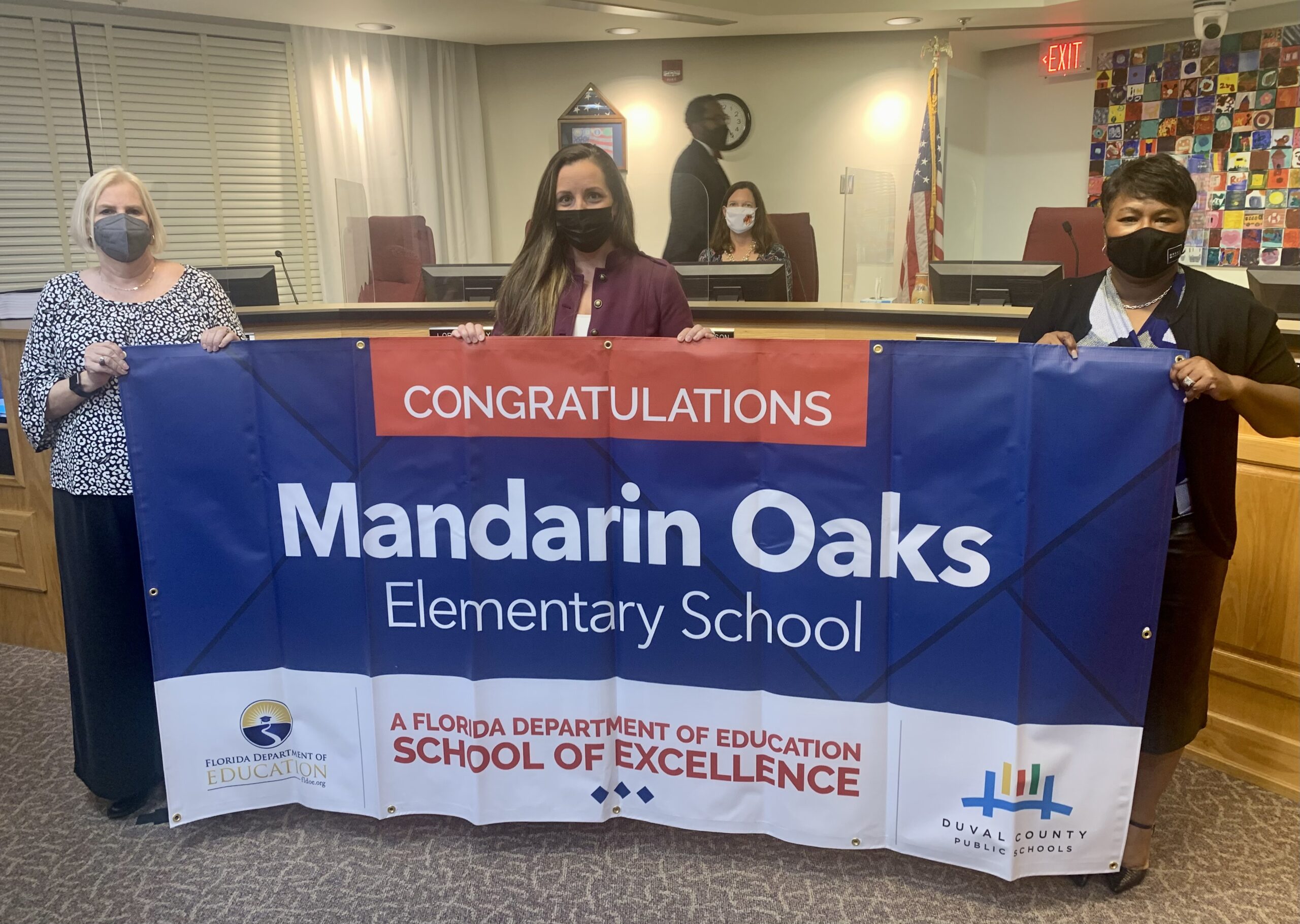 Superintendent, Board Member and school administrator hold banner Congratulations Mandarin Oaks Elementary School a Florida Department of Education School of Excellence