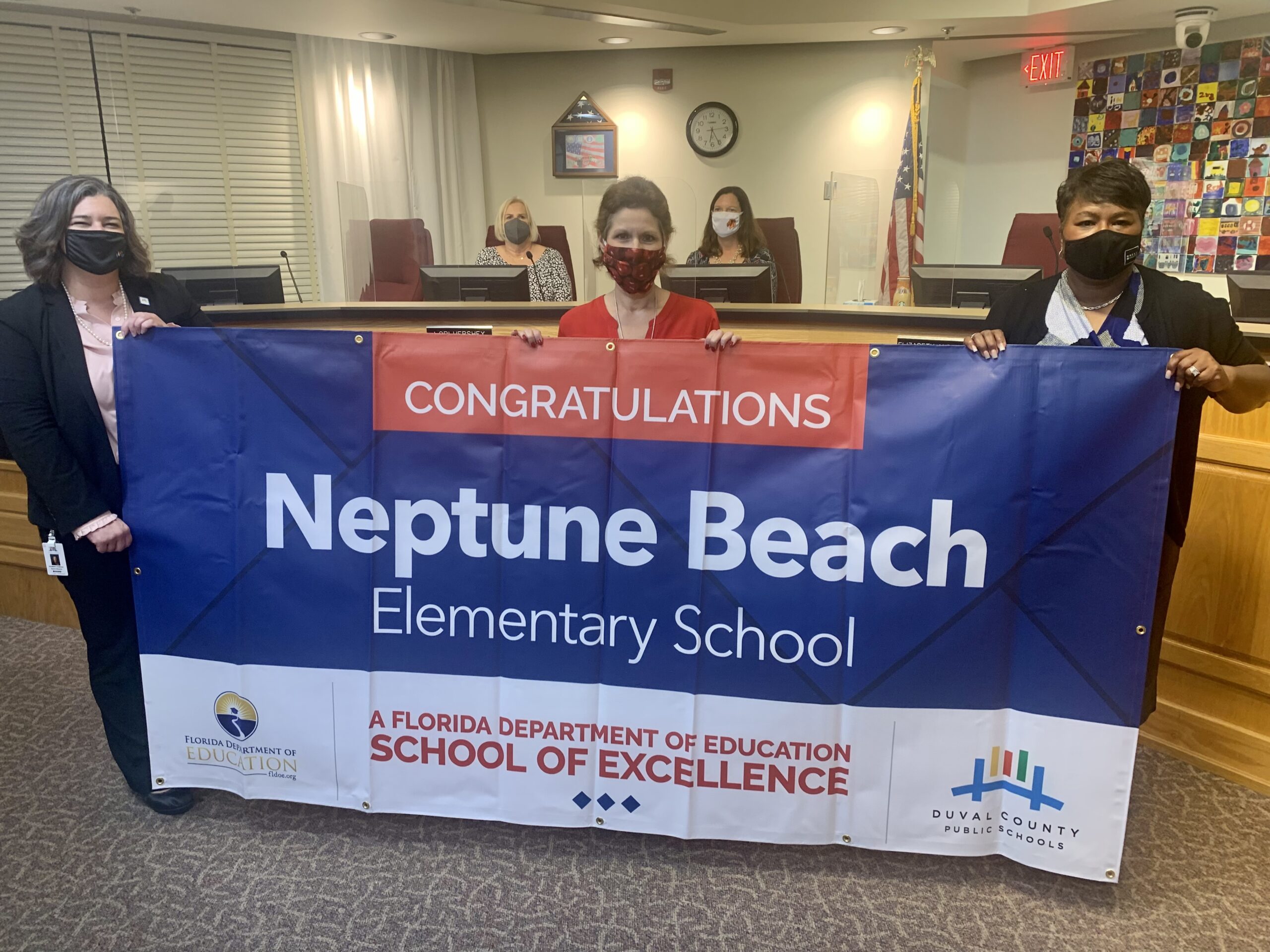 Superintendent, Board Member and school administrator hold banner Congratulations Neptune Beach Elementary School a Florida Department of Education School of Excellence