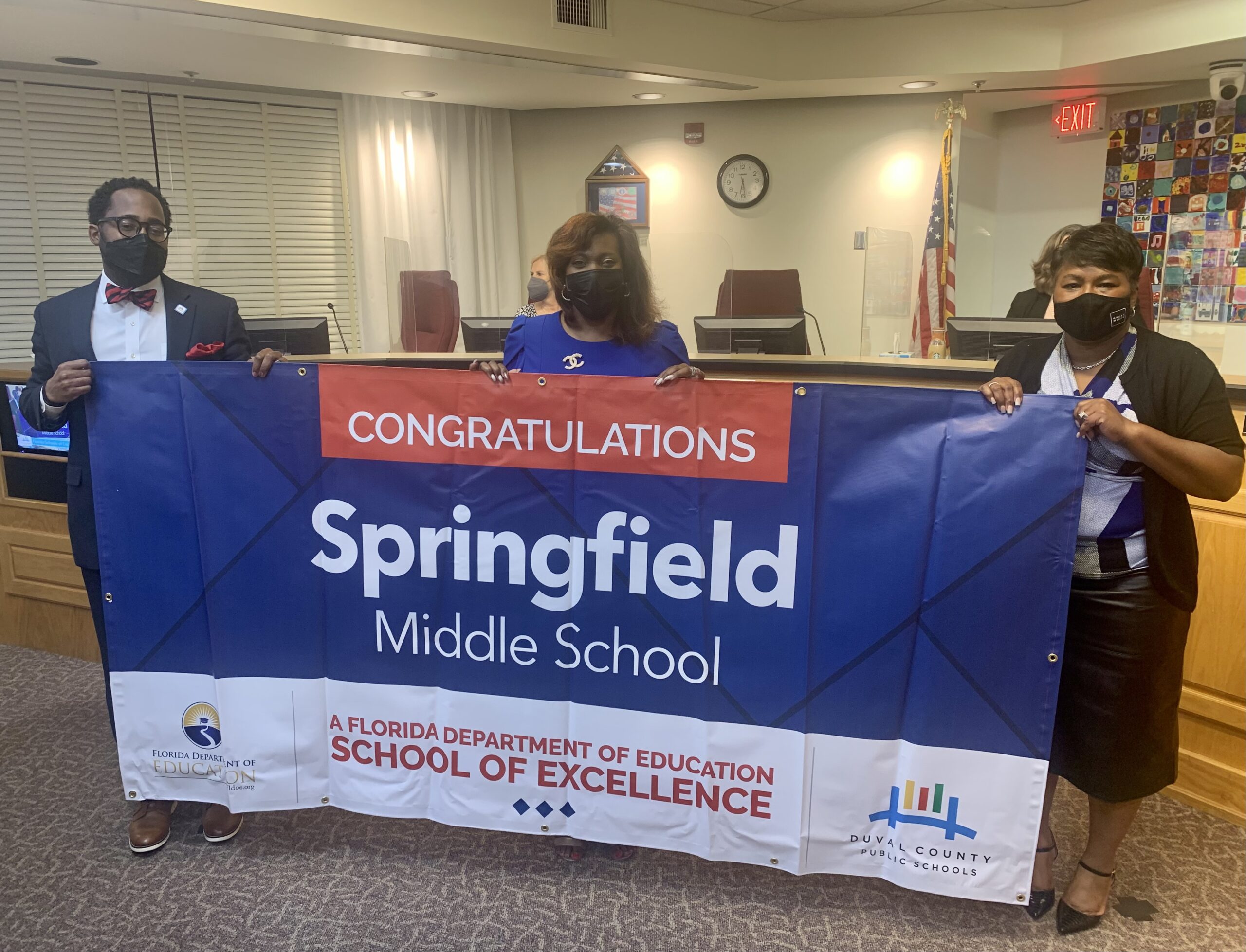 Superintendent, Board Chairman and school administrator hold banner Congratulations Springfield Middle School a Florida Department of Education School of Excellence