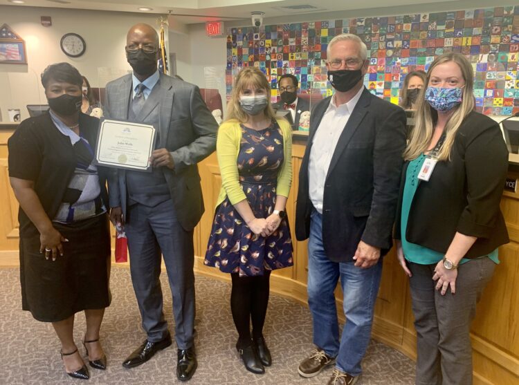 Honoree John Wells stands holding his certificate with Superintendent Dr. Greene and representatives from Embry-Riddle