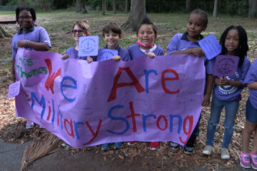 Anchor Academy students holding up a banner that reads "We are Military Strong"