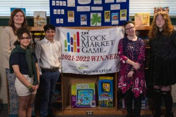 The Grasp Academy team in front of a banner congratulating them on their top prize