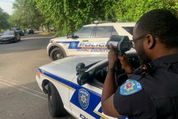 Traffic safety officer uses radar gun to monitor traffic speed entering school