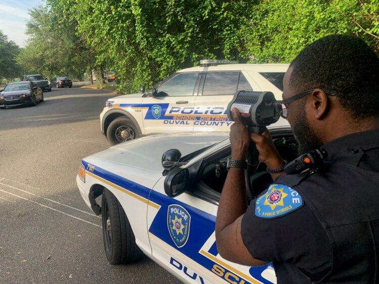 Traffic safety officer uses radar gun to monitor traffic speed entering school